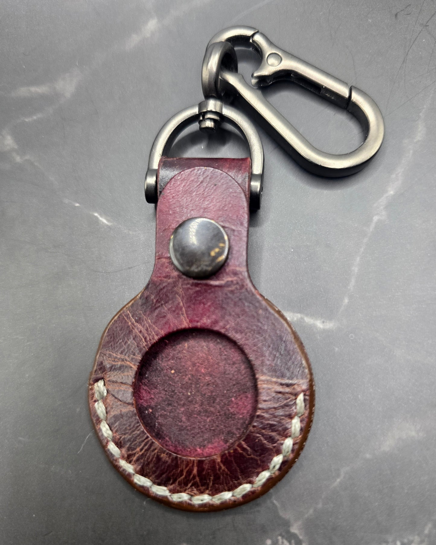 Brown vegetable tanned leather Apple air tag case on a stainless steel keychain.