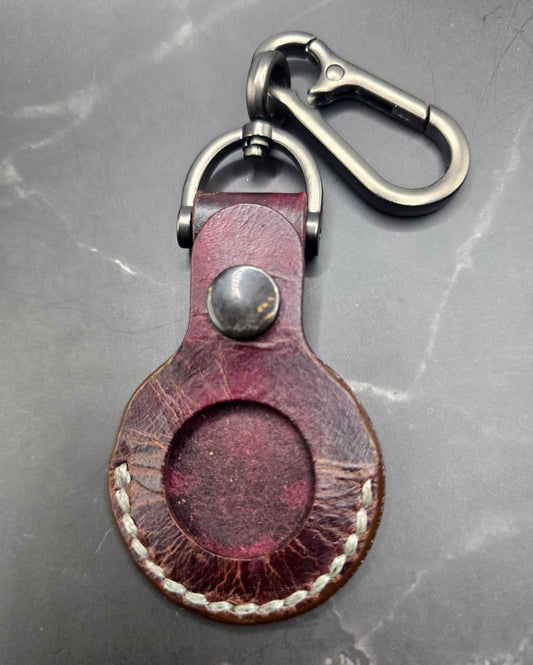 Brown vegetable tanned leather Apple air tag case on a stainless steel keychain.
