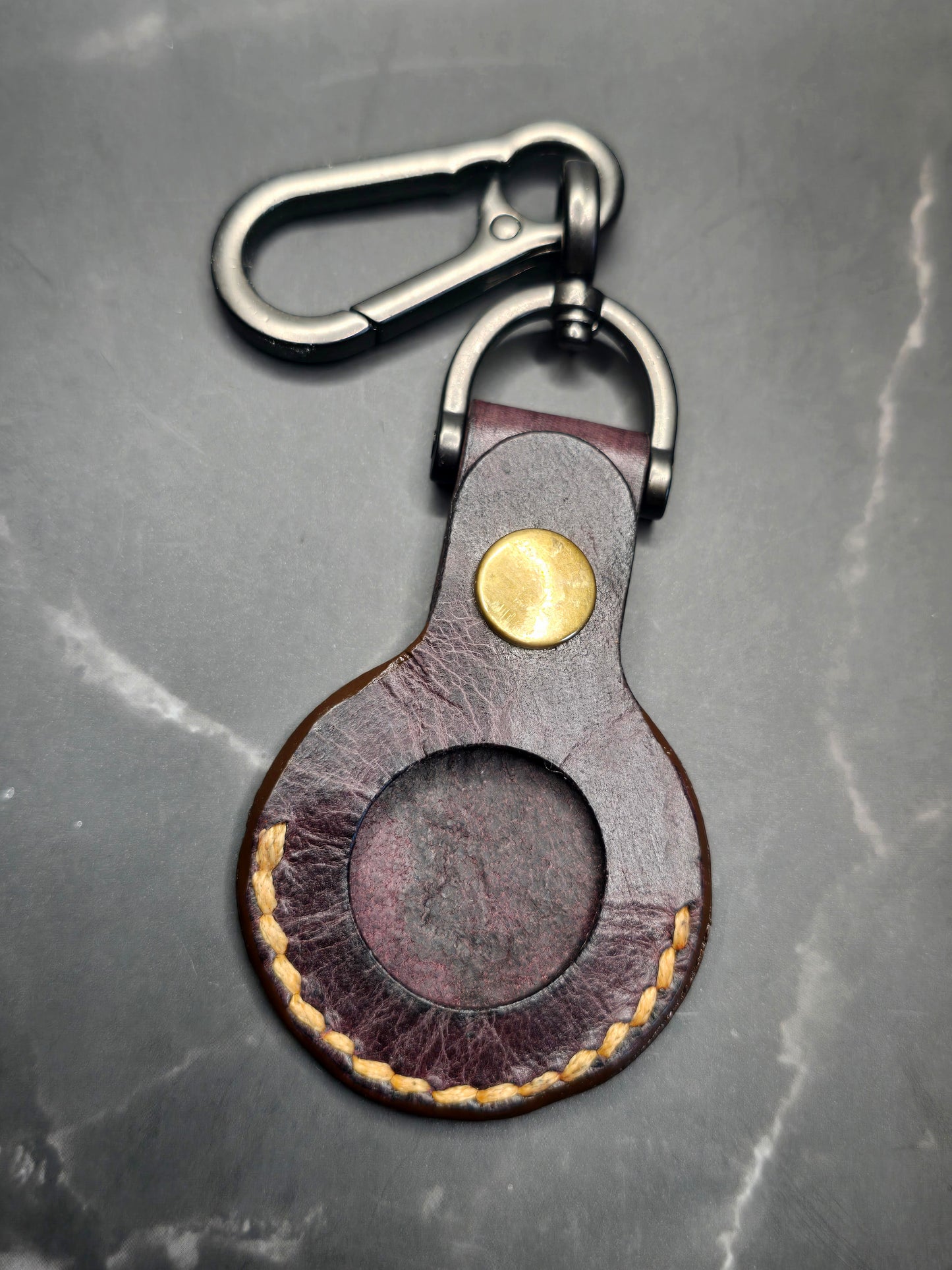 Brown vegetable tanned leather Apple air tag case on a stainless steel keychain.
