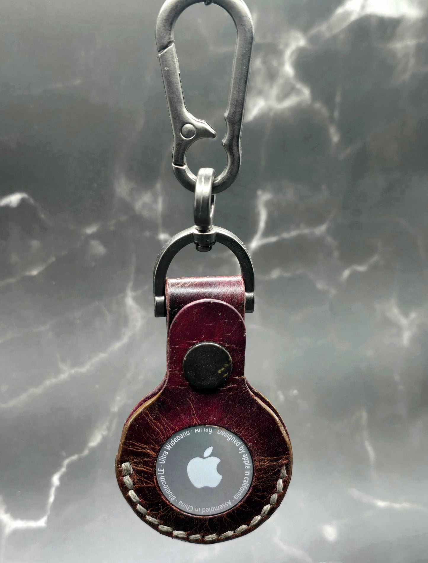 Brown vegetable tanned leather Apple air tag case on a stainless steel keychain with an apple air tag inserted.
