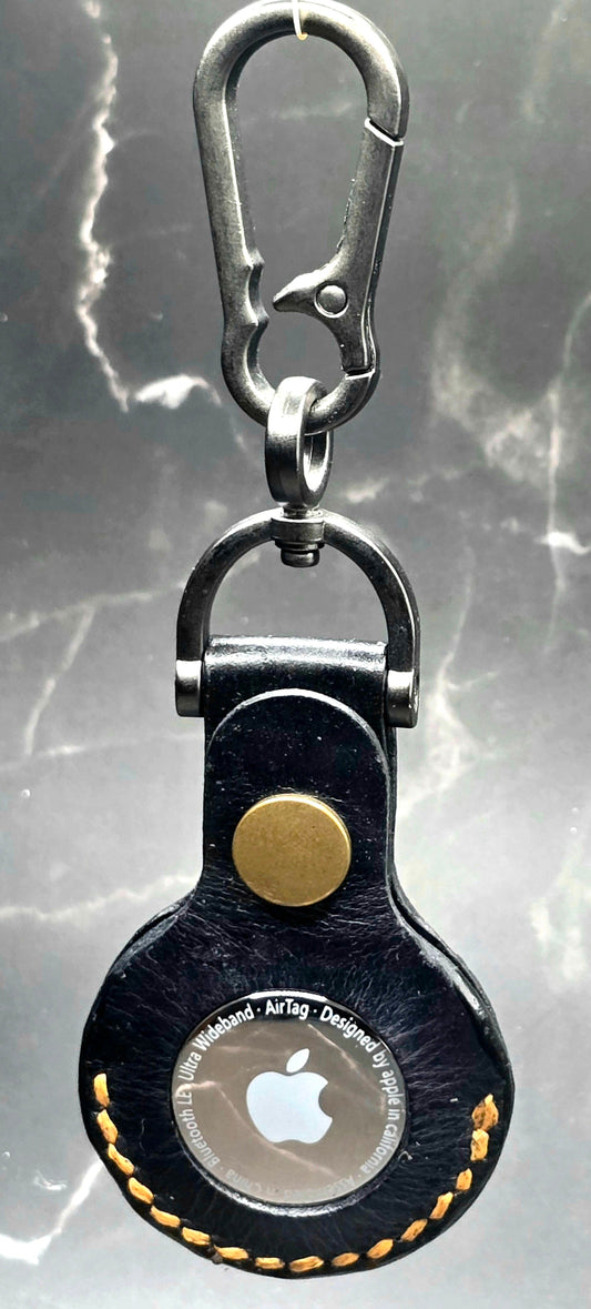 Black veg-tan leather apple airtag case with orange stitching on a keychain.