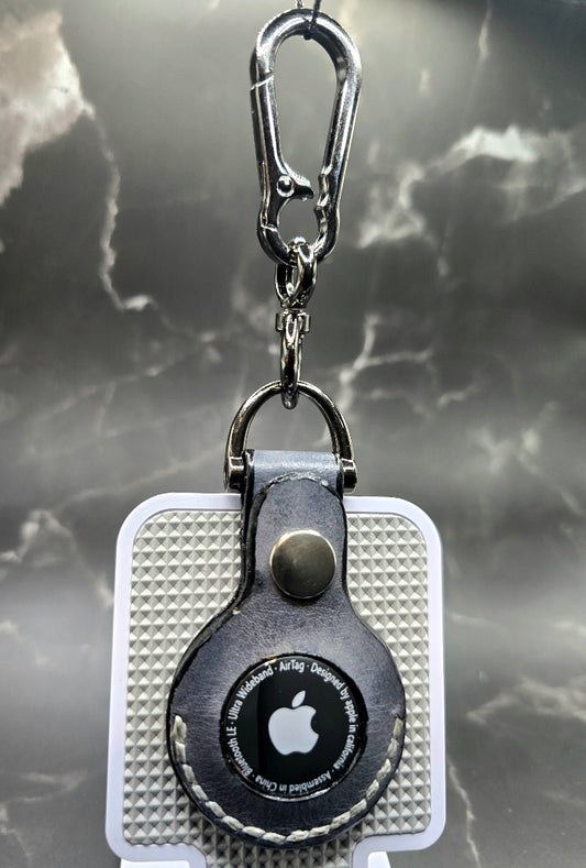 Black vegetable tanned leather Apple air tag case on a stainless steel keychain with apple air tag inserted.