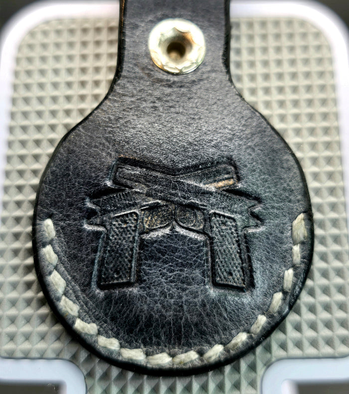 Black veg-tanned leather apple air tag case with 2 guns stamped into it.