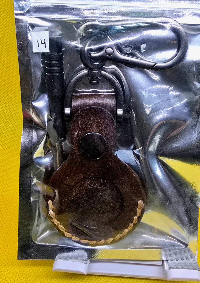 Brown veg-tanned leather apple airtag holder with lobster clasp style keychain in a bag with a small screwdriver.