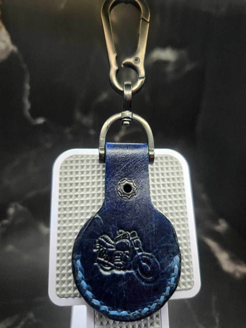 Navy blue veg-tan leather apple airtag case with a motorcycle stamped into it on a stainless steel keychain.