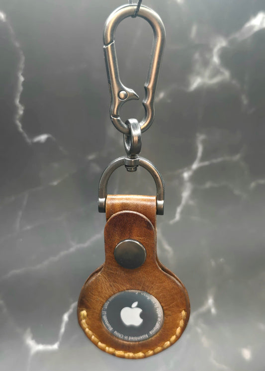 Brown vegetable tanned leather Apple air tag case on a stainless steel keychain with an apple air tag inserted hanging from a solid stainless steel lobster clasp keychain.