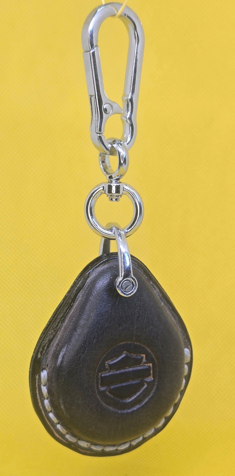 Gray veg-tan leather key fob case for Harley Davidson motorcycles hanging on a solid chrome colored stainless steel lobster clasp keychain.