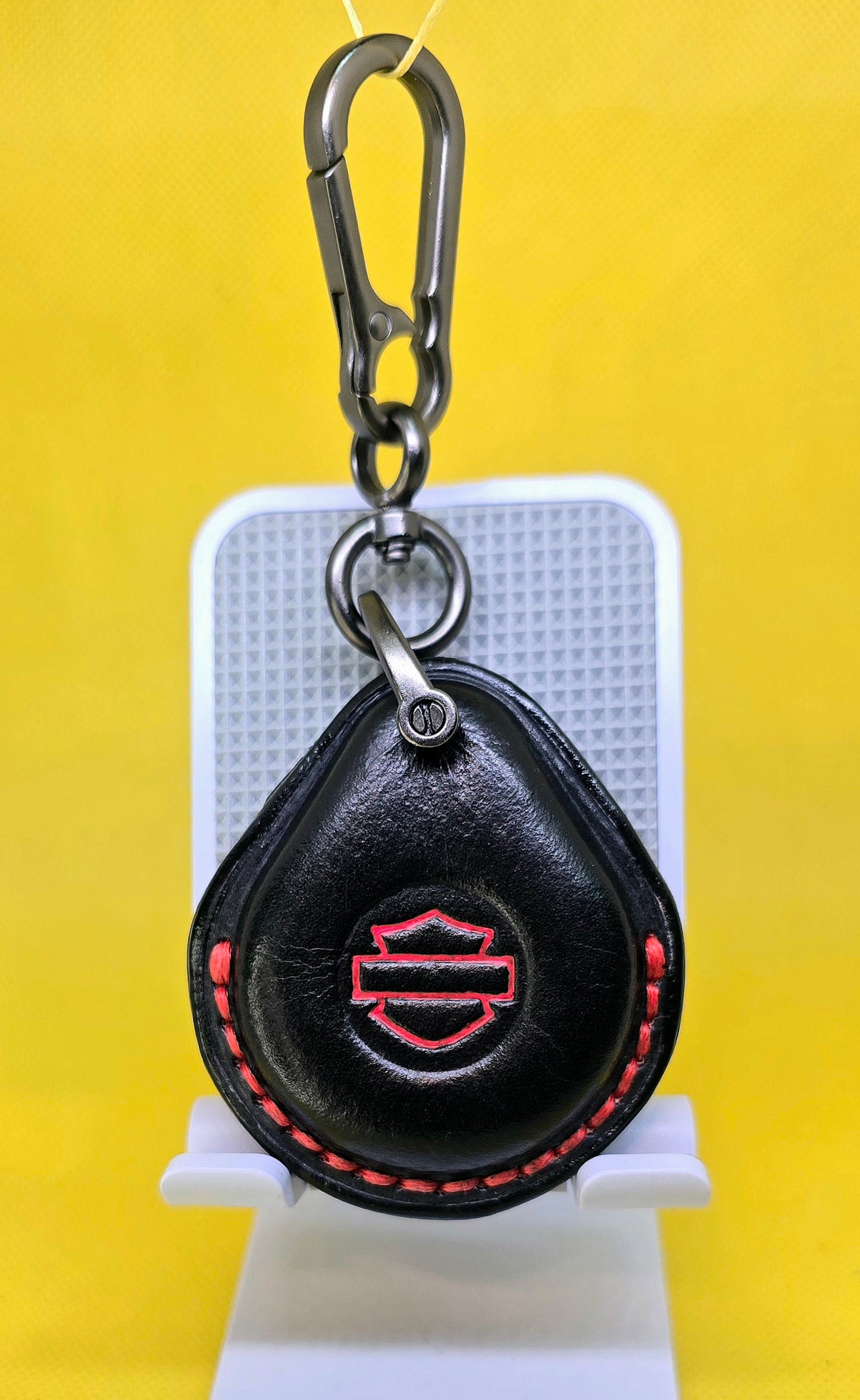 Black and red vegetable tanned leather key fob case for Harley Davidson motorcycles with red stitching hanging on a lobster clasp keychain.