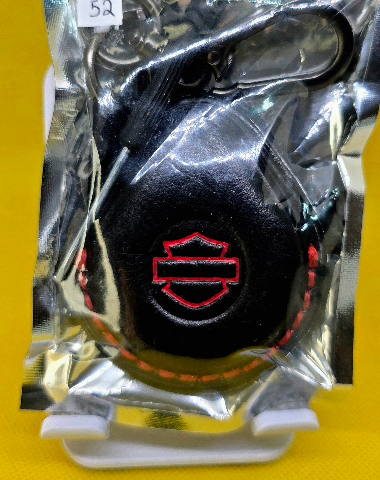 Black and red veg-tan leather key fob case for Harley Davidson motorcycles with red stitching and logo in retail packaging with included lobster clasp keychain and mini screwdriver.