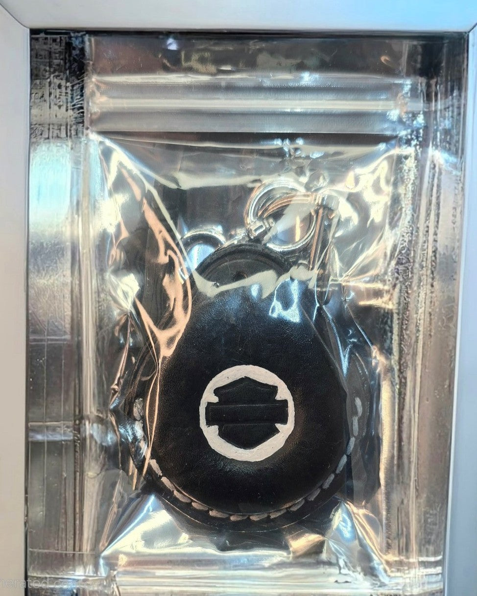 Black and white veg-tan leather key fob case for Harley Davidson motorcycles with white stitching in it's retail packaging with a solid, stainless steel lobster clasp style stainless steel keychain and the included mini screwdriver.