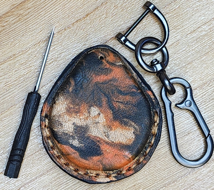 Back view of a leather key fob case for Harley Davidson motorcycles in an orange and black camo style. Vue arrière de l'étui porte-clés en cuir pour moto Harley Davidson