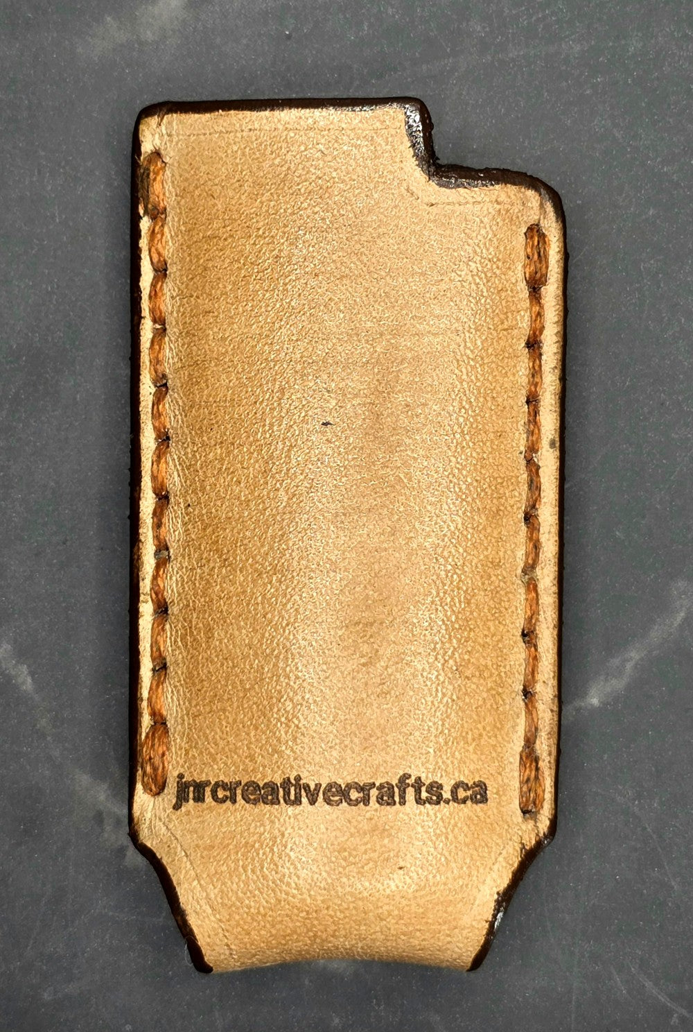Light brown vegetable tanned leather lighter case for bic lighters with skull and crossbones stamped into it. Crafted in Canada by JnRcreativeCrafts.
