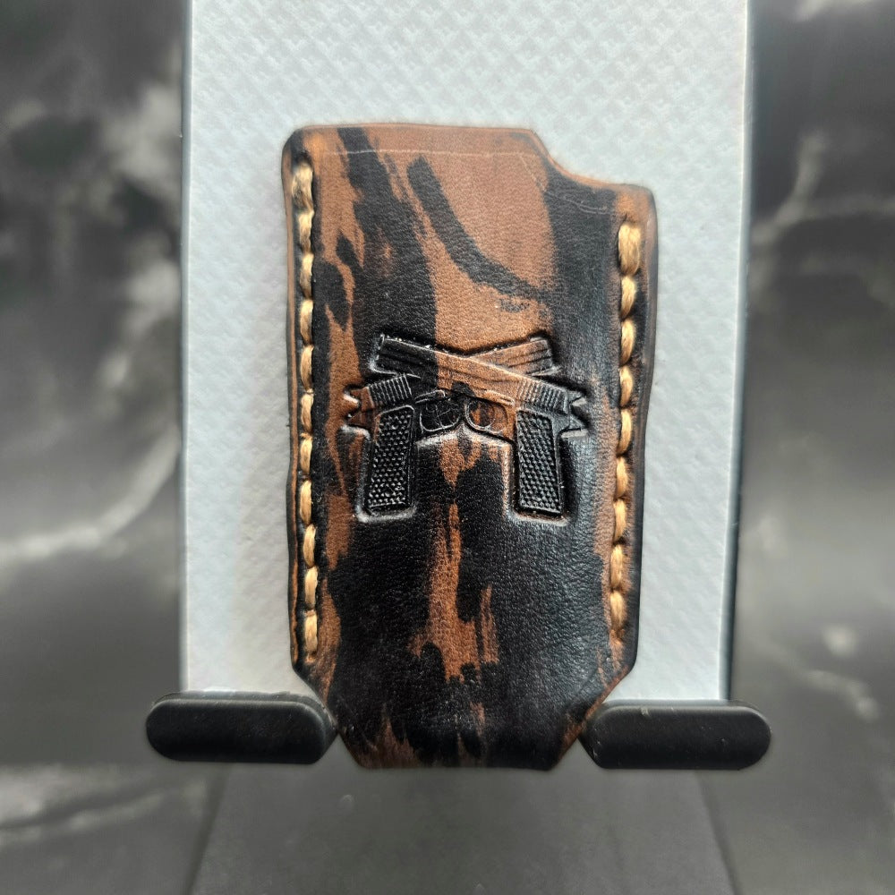 Black and brown camo-style veg-tan leather lighter case for bic lighters with a pair of handguns stamped into it.