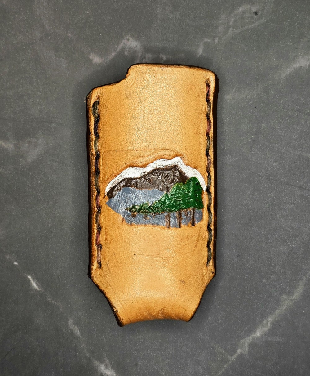 Veg-tan leather lighter case for bic lighters with mountain and trees hand painted onto it.