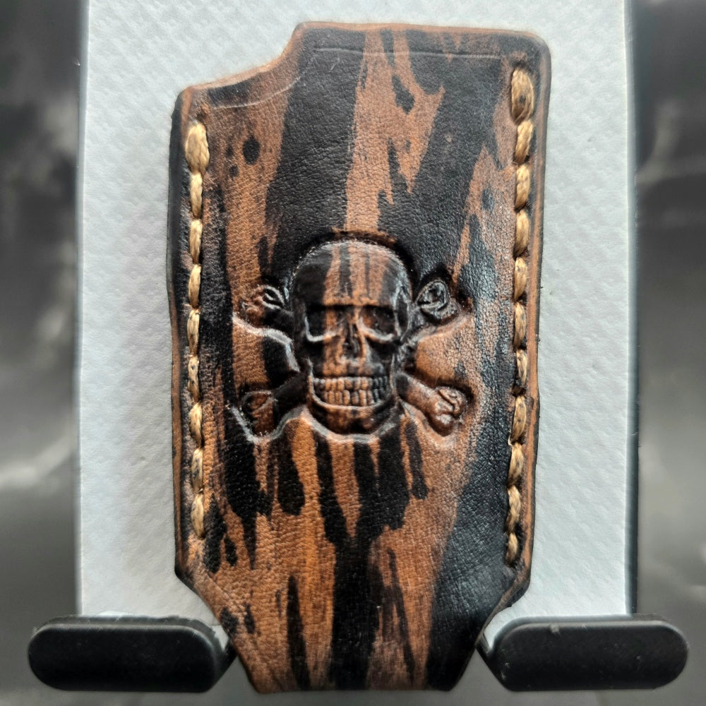 Black and brown camo-style veg-tan leather lighter case for bic lighters with a skull and crossbones stamped into it.