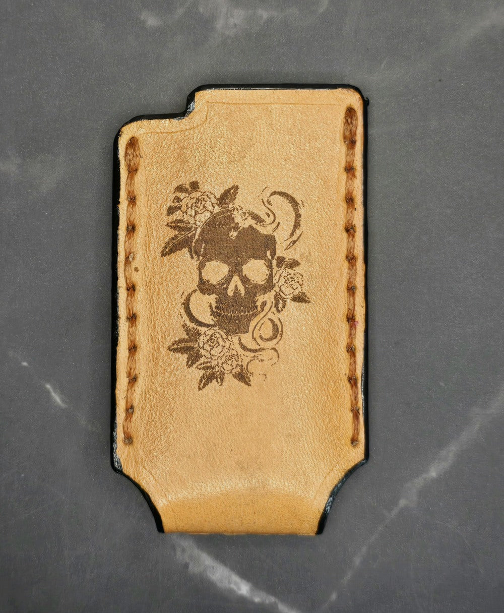 Light brown vegetable tanned leather lighter case for bic lighters with a skull and roses laser engraved on it.
