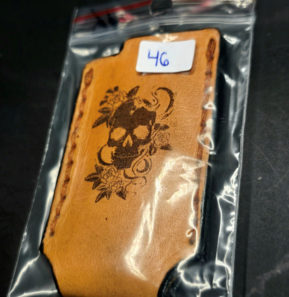 Light brown vegetable tanned leather lighter case for bic lighters with a skull and roses laser engraved on it.