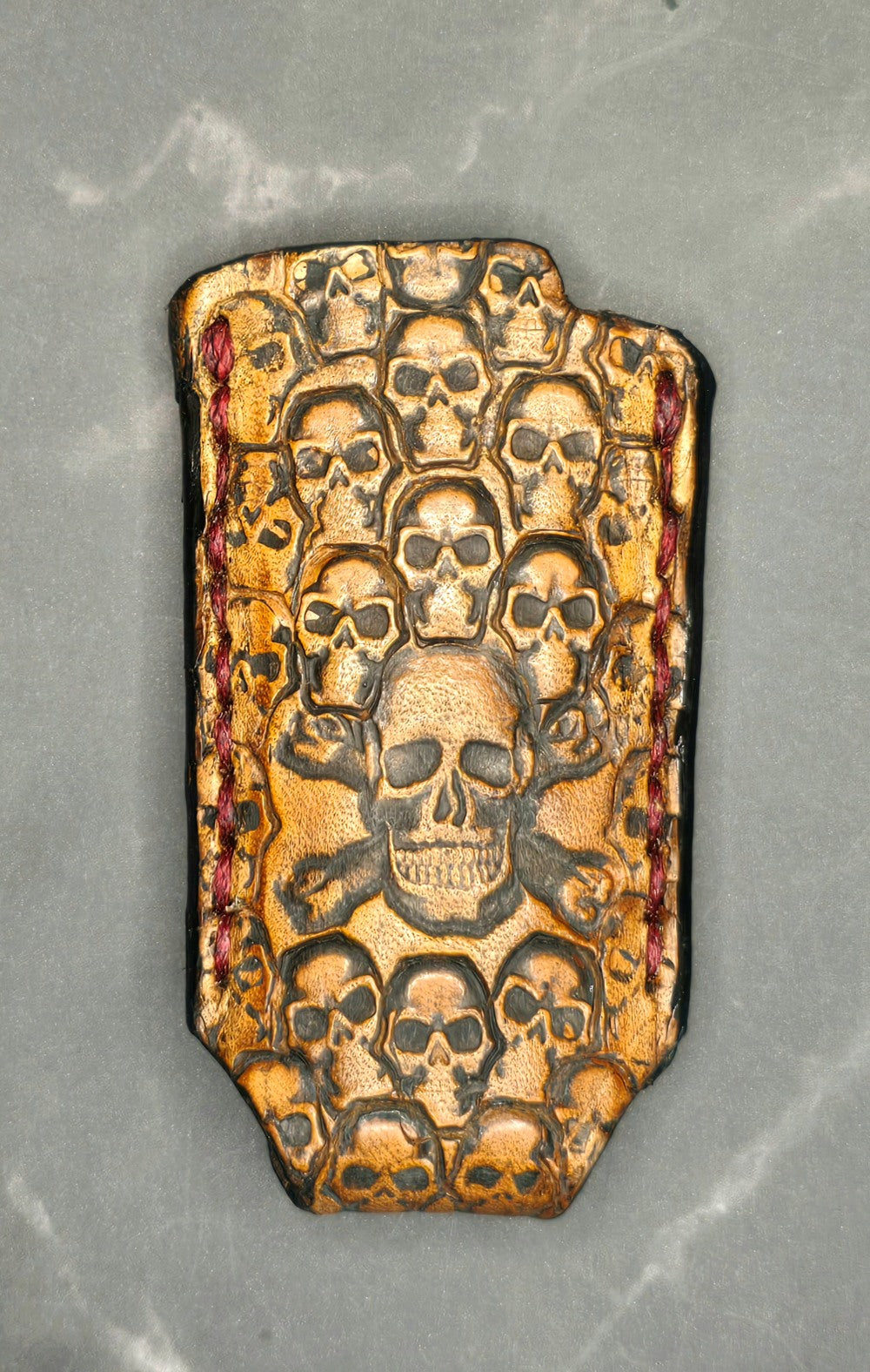 Light brown vegetable tanned leather lighter case for bic lighters with skulls stamped into it. Canadian made.