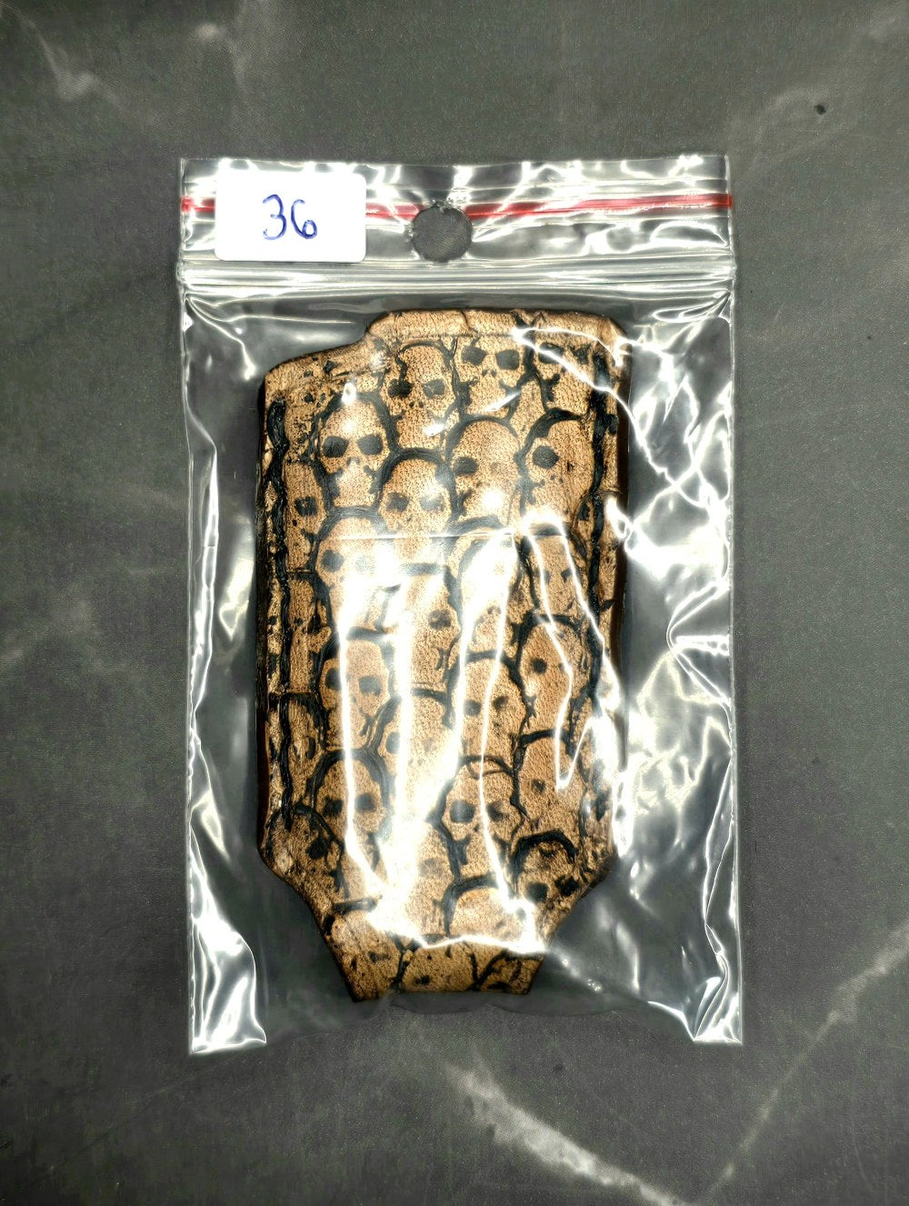 Light brown veg-tan leather lighter case for Bic lighters with skulls stamped into it in retail packaging Crafted in Canada by JnRcreativeCrafts.