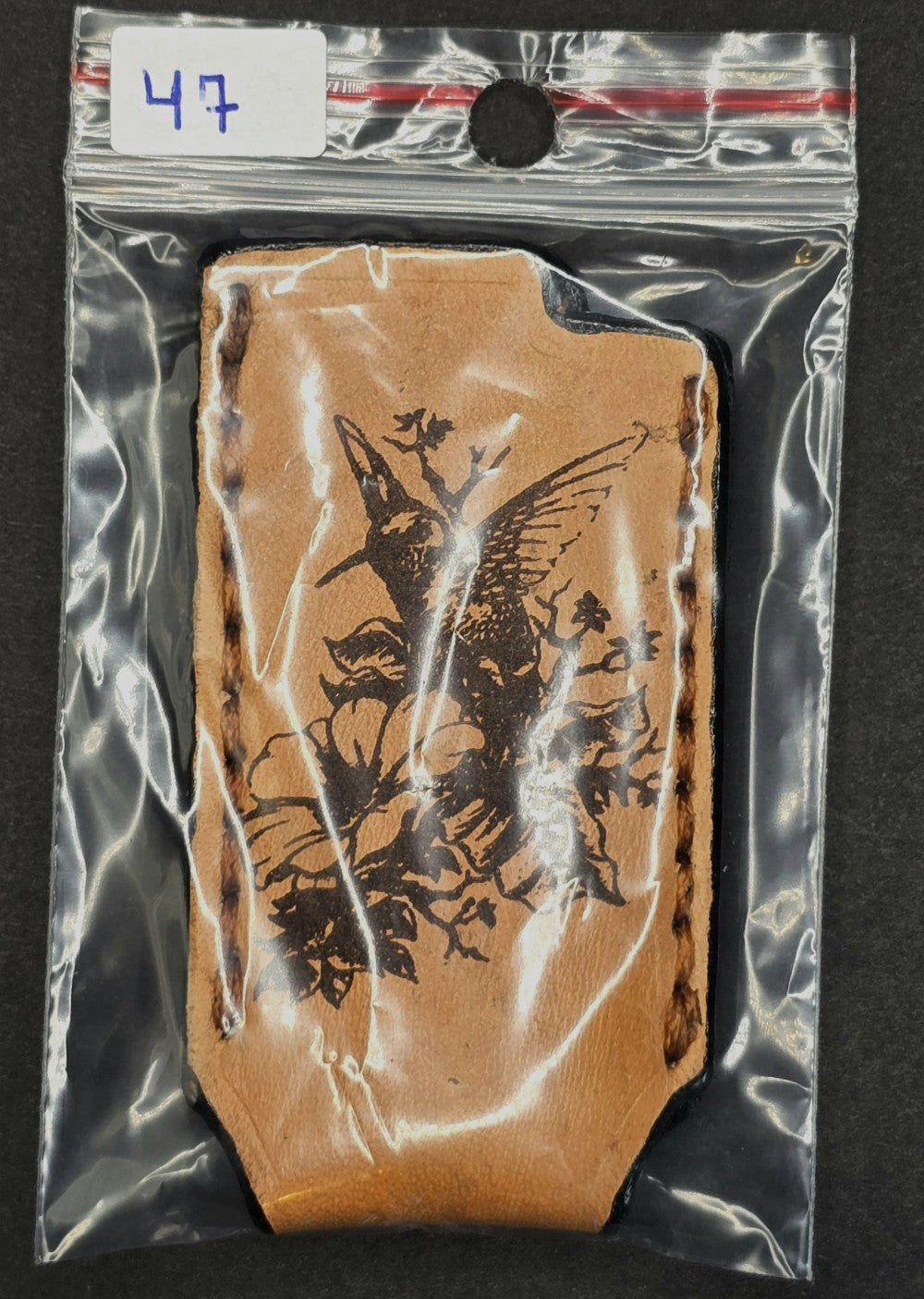 Light brown veg-tan leather Bic lighter case with a hummingbird laser engraved into it in retail package.