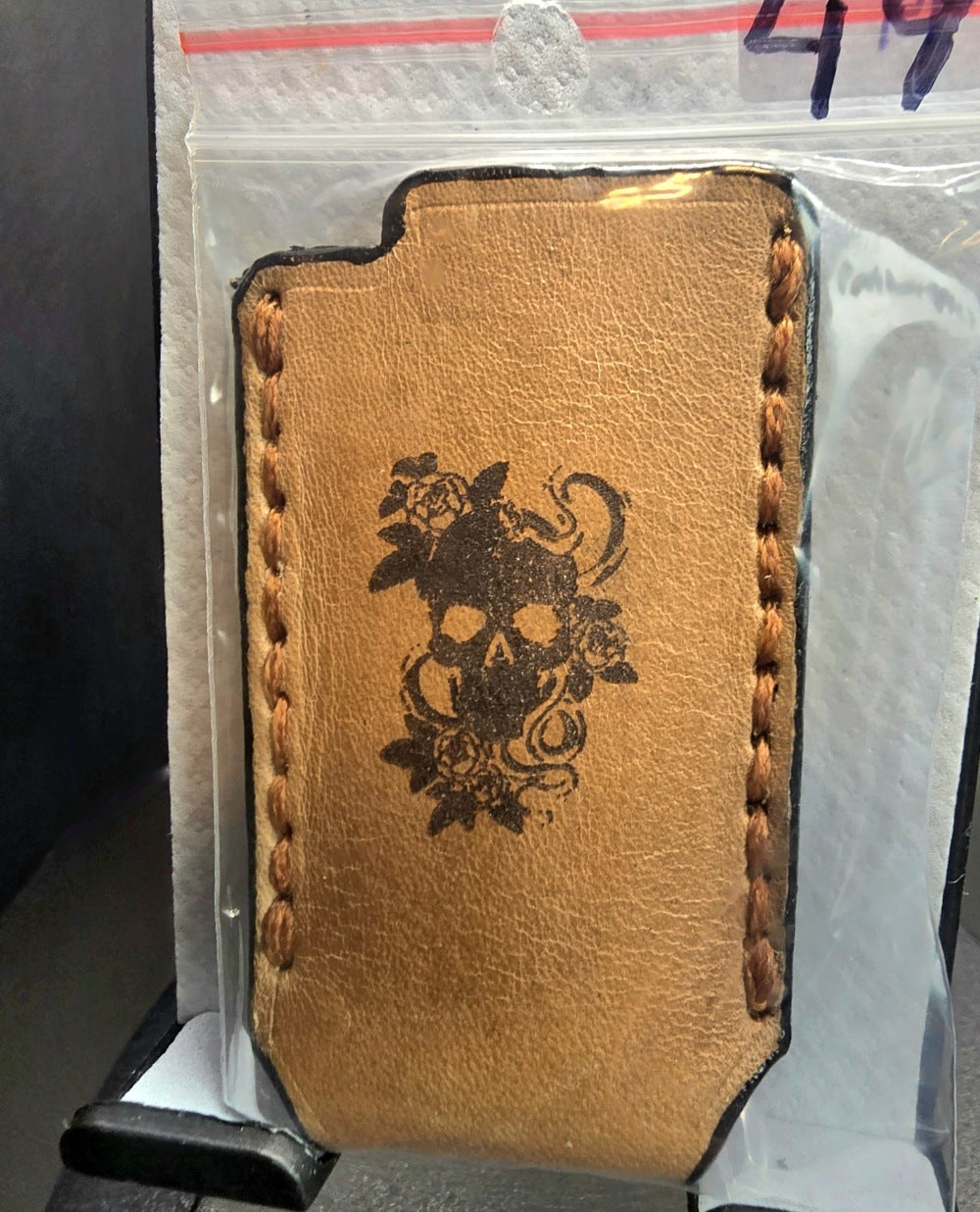 Light brown veg-tanned leather bic lighter case with a skull and roses laser engraved on it.