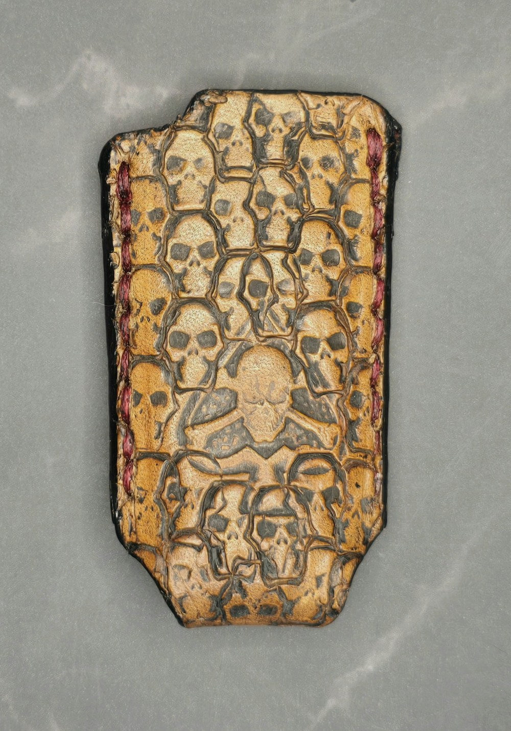 Light brown vegetable tanned leather lighter case for bic lighters with many skulls stamped into it and an Ace of spades in the middle. Crafted in Canada by JnRcreativeCrafts.