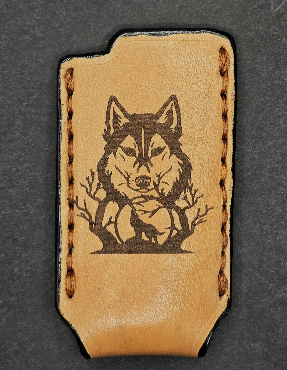 Light brown veg-tan leather Bic lighter case with a wolf laser engraved into it.
