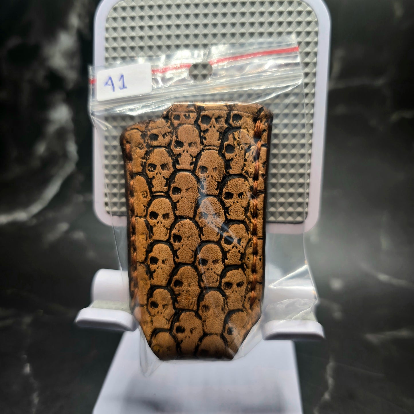 Light brown vegetable tanned leather lighter case for bic lighters with skulls stamped into it in retail package.