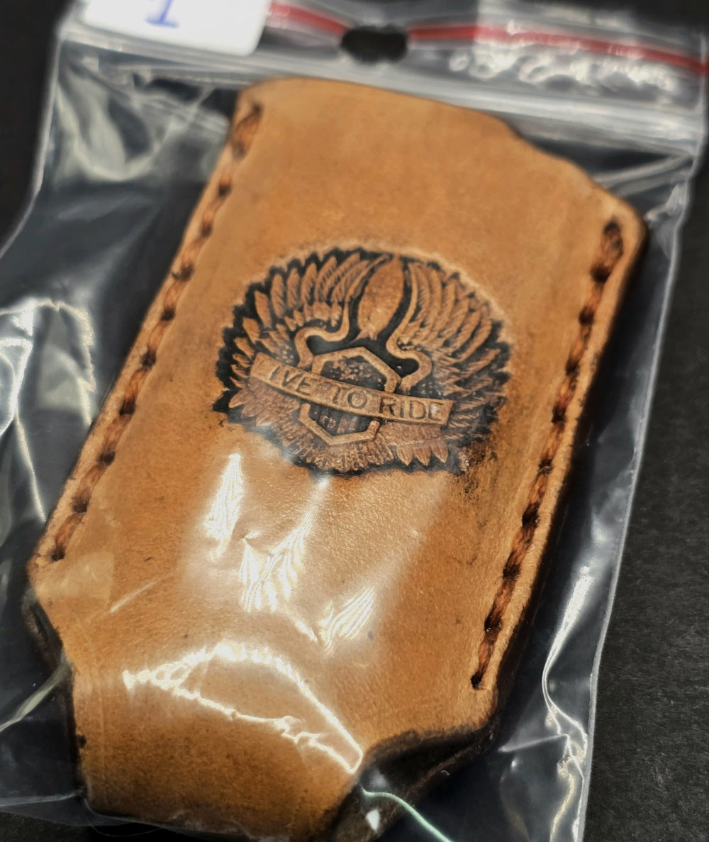 Picture of a veg-tan leather bic lighter case with a "Live to Ride" stamped into it with wings in retail packaging.
