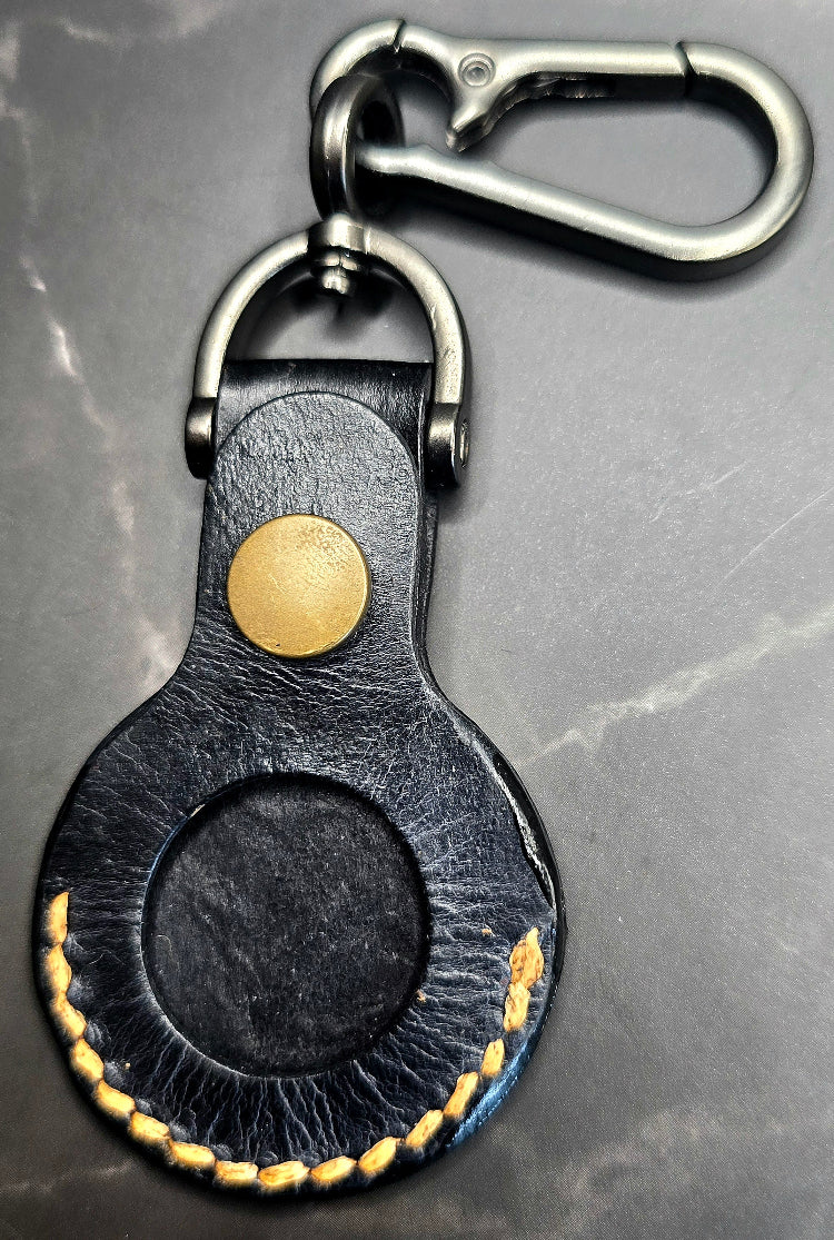 Black veg-tan leather apple airtag case with orange stitching on a keychain.