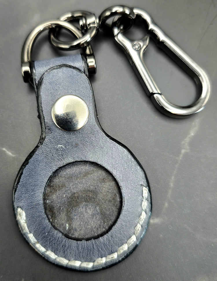 Charcoal veg-tanned leather apple air tag case without air tag inserted on a stainless steel keychain.