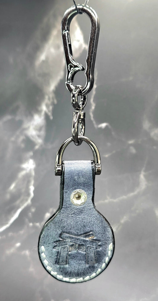 Black veg-tanned leather apple air tag case with a motorcycle stamped into it on a stainless steel keychain.
