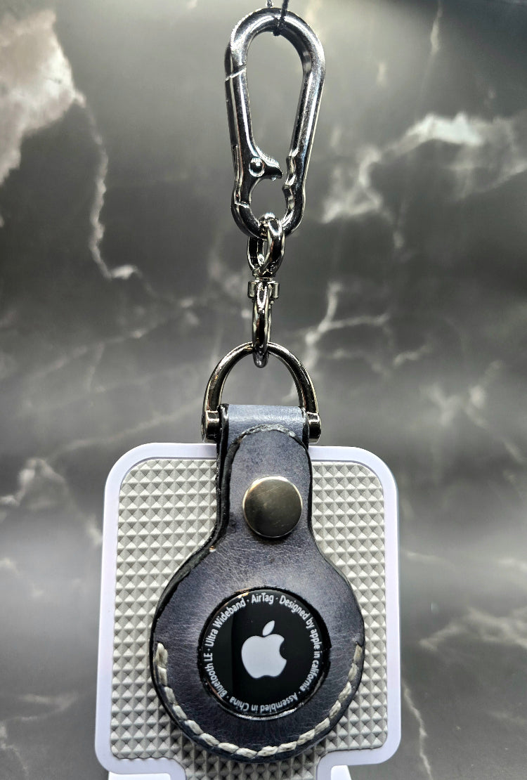 Black vegetable tanned leather Apple air tag case on a stainless steel keychain with apple air tag inserted.
