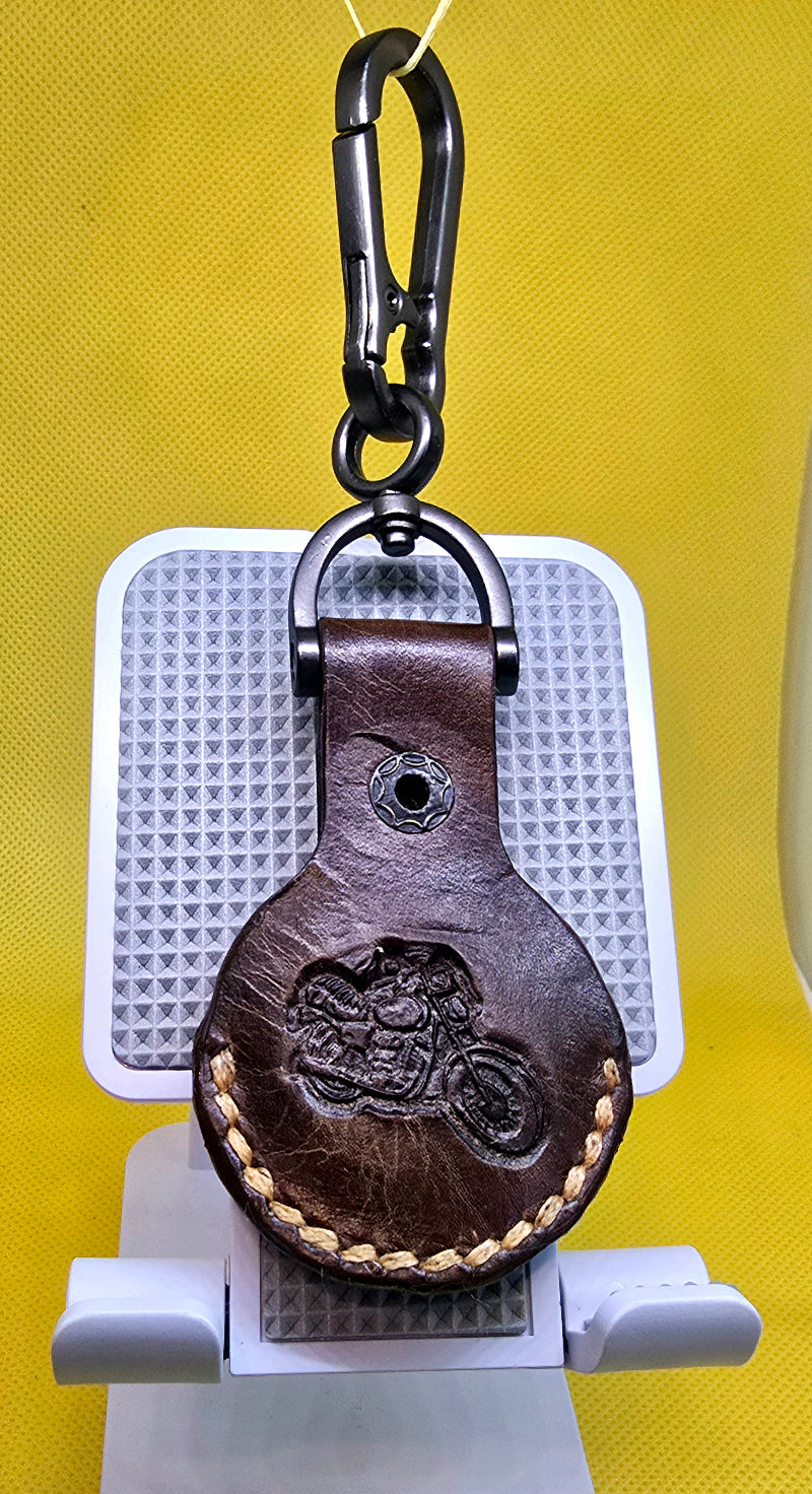 Brown Veg-tan leather apple airtag case with a motorcycle stamped into it on a stainless steel keychain.