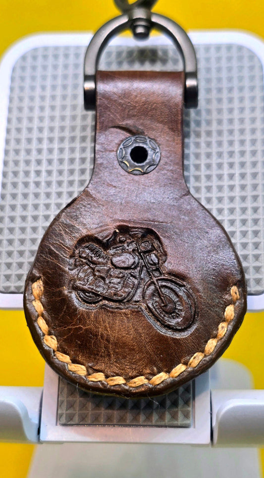 Brown Veg-tan leather apple airtag case with a motorcycle stamped into it on a stainless steel keychain.
