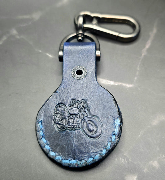 Navy blue Veg-tan leather apple airtag case with a motorcycle stamped into it on a stainless steel lobster clasp keychain.