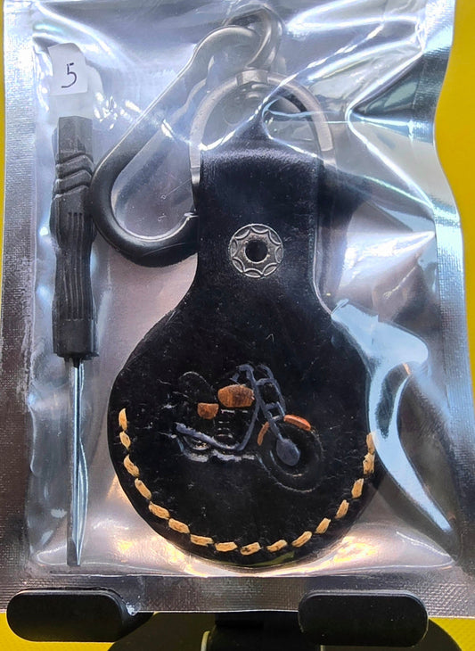 Black vegetable tanned leather apple air tag case with orange stitching, a stamped motorcycle hand-painted orange and black on a solid stainless steel keychain.