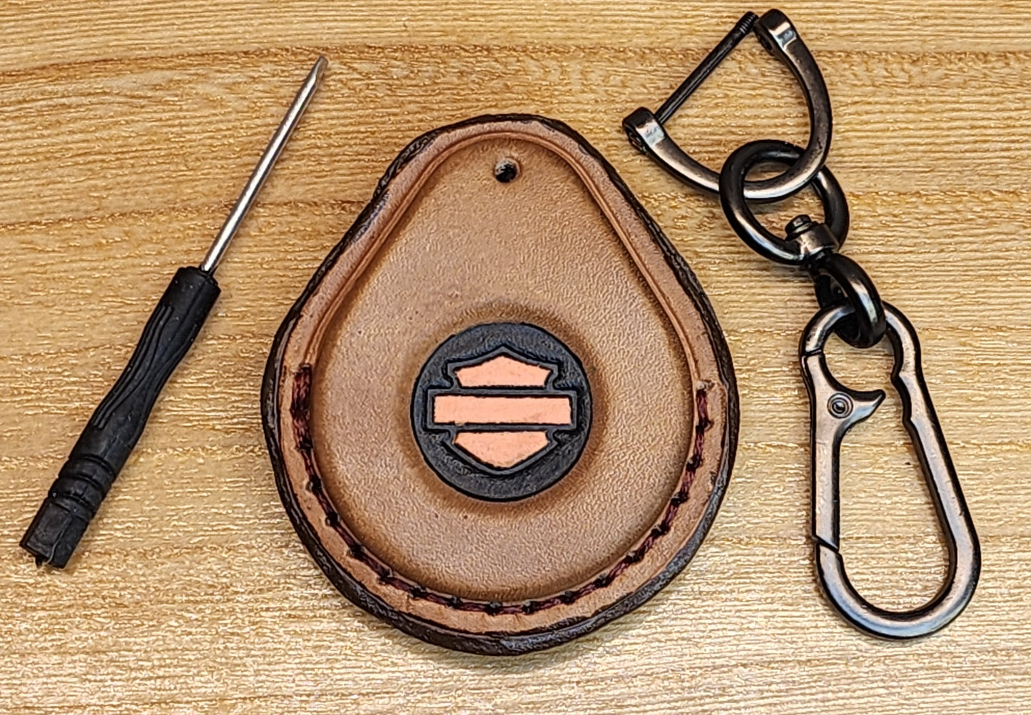 Front view of a brown, black and orange logo leather Harley Davidson key fob case with mini screwdriver and keychain