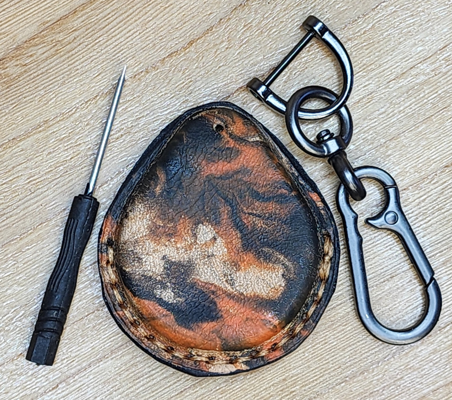 Back view of a leather key fob case for Harley Davidson motorcycles in an orange and black camo style. Vue arrière de l'étui porte-clés en cuir pour moto Harley Davidson