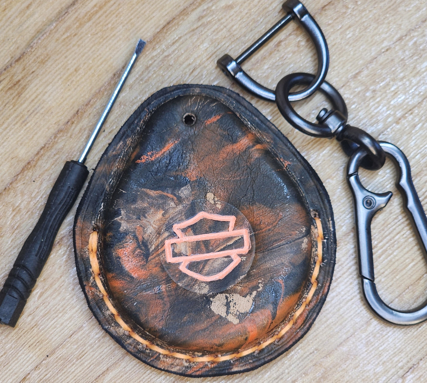 Front view of camo style orange and black leather key fob case for Harley Davidson motorcycles with screwdriver and keychain . Étui porte-clés pour Moto Harley Davidson.