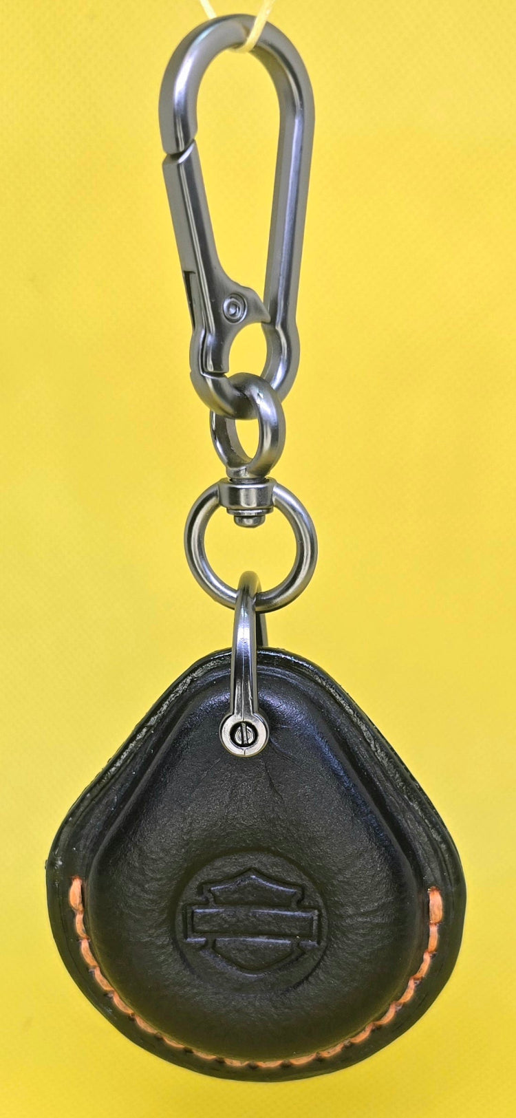 Black veg tan leather key fob case for Harley Davidson motorcycles with orange stitching on a keychain.