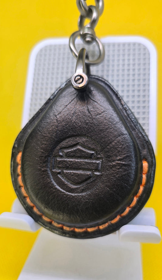 Black veg-tan leather key fob case for Harley Davidson motorcycles with orange stitching on a keychain.