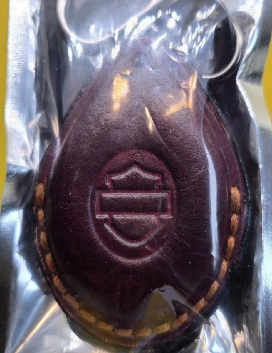 Burgundy veg-tan leather key fob case for Harley Davidson motorcycles in retail packaging with the included stainless steel lobster clasp keychain and mini screwdriver.