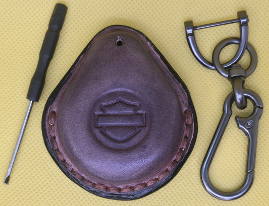 Picture of a mahogany colored  vegetable tanned leather key fob case for Harley Davidson motorcycles on a table with the included stainless steel keychain and screwdriver.