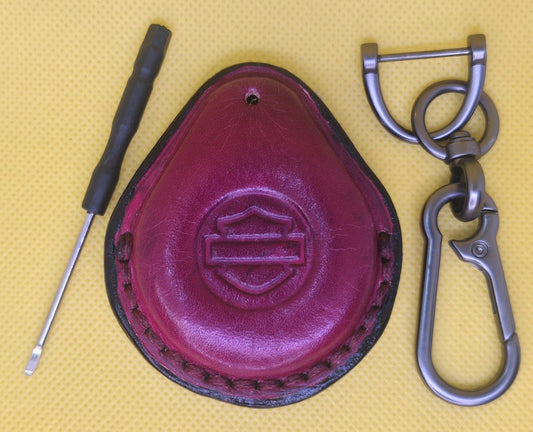 Picture of an ox blood colored vegetable tanned leather key fob case for Harley Davidson motorcycles on a table with the included stainless steel lobster clasp  keychain and screwdriver.