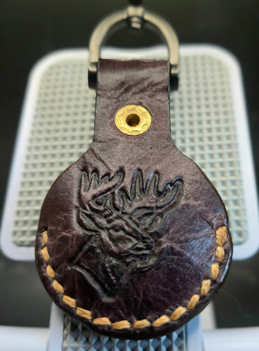 Brown vegetable-tanned leather apple air tag case with a picture of a deer stamped into it.