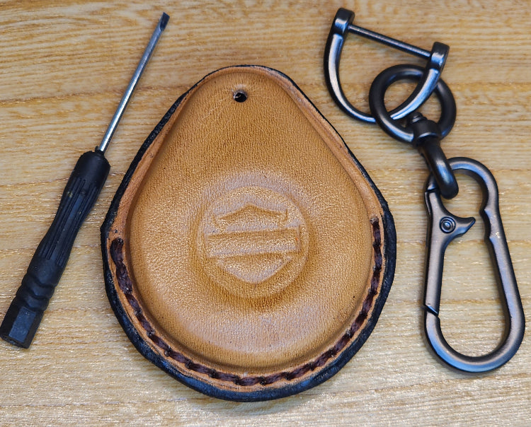 Light brown veg-tan leather key-fob case with black stitching for Harley Davidson motorcycles with a keychain and screwdriver. 