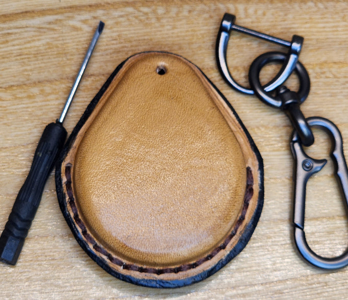 Back view of a light brown vegetable tanned leather key-fob case with black stitching for Harley Davidson motorcycles with a keychain and screwdriver. 