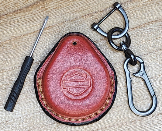 Orange veg tan leather key fob for Harley Davidson motorcycles with tan stitching on a keychain with a small screwdriver next to it.