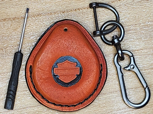 Orange and black veg-tan leather key-fob case with black stitching for Harley Davidson motorcycles with a keychain and screwdriver. 